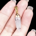 Facet cut natural crystal bullet pendant with golden metal cap held in hand - India Agate