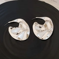 Makroaufnahme großer abstrakter unregelmäßiger geometrischer Silberohrringe mit Hammerschlag - Silber