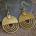 Vintage bronze geometric earrings with layered round hollow design on rustic stone background - Antique Bronze