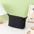 Black quilted dumpling-shaped cosmetic bag with tassel zipper on a desk setting - Black Dumpling Bag