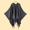 Deep grey knitted shawl cloak with tassel fringe hanging on a wooden hanger - Gray
