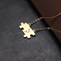 Macro shot of gold puzzle piece pendants on textured black leather background - O Chain / Gold