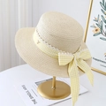 Detail of woven straw hat featuring yellow plaid ribbon, lace trim, and a gold V charm - Beige