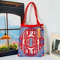 Close-up of knit tote bag featuring red white blue geometric patterns and a red shoulder strap - New Chinese Red