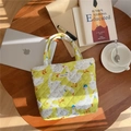 Dettaglio borsa trapuntata verde con stampa oca e etichetta simple wish su tavolo in legno - Oca Anatra (Verde chiaro)