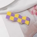 Makro-Detail der welligen Haarklammer mit gelb-violettem Schachbrettmuster auf Satin - Lila & Gelb