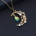 Détail du pendentif lune et étoile doré avec cristal bleu-vert sur cuir noir texturé - Vert