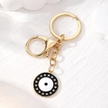 Portachiavi dorato con malocchio e strass luccicanti su superficie bianca elegante - Occhio Strass Nero Bianco