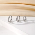 Detailed view of three silver hoop earrings with cubic zirconia on silk fabric - Three-Piece Set / Silver