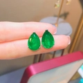 Elegant pear-cut emerald stud earrings held in hand featuring high-clarity green gemstones - Earrings Pair / Emerald
