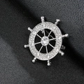 Close-up of a silver ship wheel brooch with sparkling rhinestones on black leather - Rudder Silver