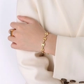 Detailopname van de gouden koffieboon armband en geometrische ring bij het model - Gouden Armband