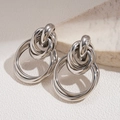 Macro detail of intertwined silver knot earrings with polished geometric metal surface - Silver (925 Sterling Silver Earring Post)