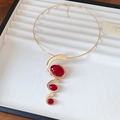 Gouden choker halsketting met drie rode ovale harsstenen op spiraalbasis - Chokerketting / Goud-Rood