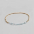 Macro detail of natural light blue faceted gemstone beads and gold beaded stretch bracelet - Transparent Apatite