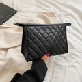 Neceser acolchado negro con cremallera sostenido sobre fondo de chaqueta beige - Negro