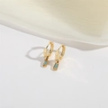 Detail of luxury gold zipper-shaped earrings with turquoise stones and silk background - Blue Zircon / Gold With Blue Zirconia