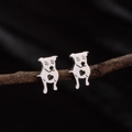 Macro shot of silver stainless steel puppy stud earrings with hollow heart details - Silver