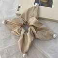 Detailed view of beige fabric square scrunchie with large white pearls on a paper background - Khaki