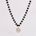 Detail of black faceted bead chain with a gold circular pendant encrusted with crystals - Pave Zircon Circle
