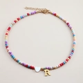 Colorful beaded necklace with gold letter R and white heart pendant on a neutral background - Letter R