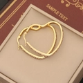 Detailed macro view of gold heart-shaped hoop earrings with sparkling rhinestones inside a box - Champagne