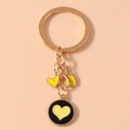 Close-up of golden metal keychain with yellow heart charms and black enamel pendant - Black and Yellow