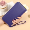 Detail of deep purple lychee pattern leather wallet with wristlet held by a person - Blue