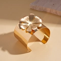 Close-up van een brede gouden open armband met een 3D gelaagde metalen bloem decoratie - IJzer / Gouden 3D Bloem Brede Armring / Goud