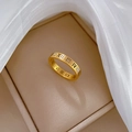 Macro detail of golden roman numeral ring with zircon stones on silk fabric - US 8 / Gold