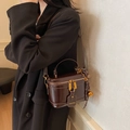 Brown mirror leather box bucket bag with golden zipper and woven charm shown on model - Coffee With Charms