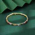 Close-up of golden chain bracelet with multi-colored rectangular and round zircons - Gold