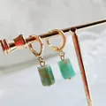 Detail view of cylindrical green natural stone earrings with golden circular hoops - Amazonite
