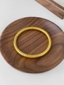 Detailed macro view of a golden grid-patterned titanium steel bangle on a wooden stand - Gold Spiral