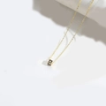 Minimalist gold necklace with a black cube pendant featuring a golden letter A - A