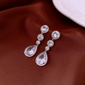 Macro detail of silver drop earrings with sparkling rhinestones on dark silk fabric - Silver-Blue