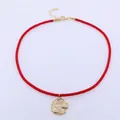 Detail of red woven cord necklace featuring a golden sun and moon artistic pendant - Red