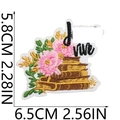 Detail of embroidered patch featuring pink flowers and golden book with dimensions - LIVE Floral Embroidery