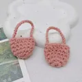 Macro detail of two pink handmade crochet mini bags on a white textured stone base - Pink