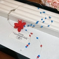 Detalle de collar de cuentas azules y rojas con un gran colgante de flor roja aterciopelada - Collar de flores de cuentas de vidrio