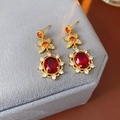 Makroaufnahme goldener Vintage-Ohrringe mit orangefarbenen Blumen und roten Edelsteinen - Ohrringe - Gold - Rot