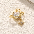 Macro shot of 18K gold heart pendant with planet ring and sparkling zircon star - White Zirconia Planet Heart