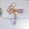 Close-up of purple butterfly keychain with tassel and sequin-filled acrylic charm - Letter I