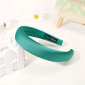 Detail of emerald green padded satin headband with Hand Made label on wooden fence - Dark Green