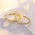 Macro shot of gold hoop earrings with sparkling white zircon insets on silk fabric - KC Gold (WG0-1294)