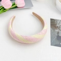 Pink and yellow woven headband made of raffia material on a minimalist white desk - Pink