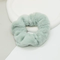 Détail d'un chouchou en fausse fourrure vert clair montrant sa texture douce et ses fibres - Vert