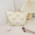 Floral makeup bag with blue bow prints and brand label in a stylish lifestyle setting - Beige Blue Bow