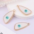 Detailed view of three golden evil eye charms with white cat eye and blue center - Knife Shape
