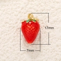 Dettaglio macro di un ciondolo a fragola da 17mm x 7mm in smalto rosso con asola dorata - Fragola